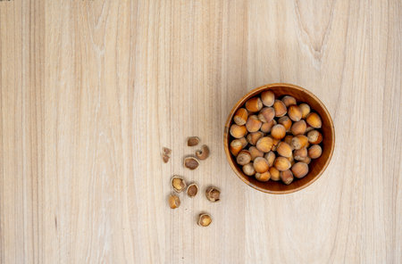 Hazelnuts in a bowl with few cracked next to it on the table. Flat lay.