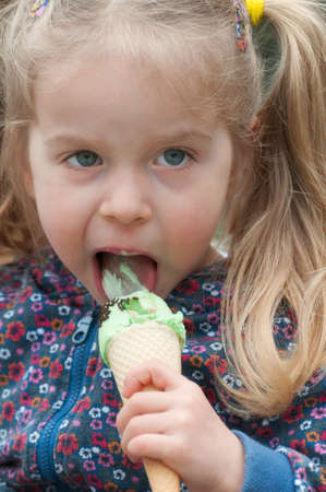 Very cute little blonde girl eating ice cream in a waffle