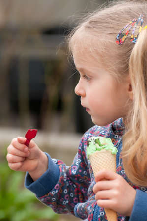 Very cute little blonde girl eating ice cream in a waffleの写真素材