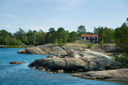 Swedish coast near Oskashamn, SmÃ¥land, with smooth polished  rocks and red farmhouseの写真素材