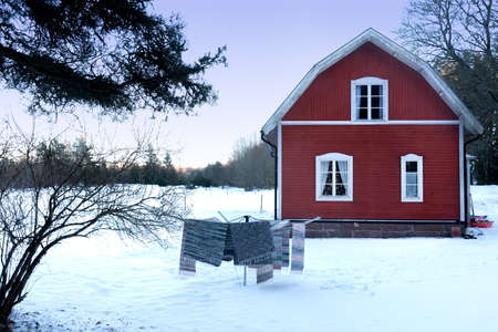 Traditional Swedish wooden house in winter with laundry hung outside in the foregroundの写真素材