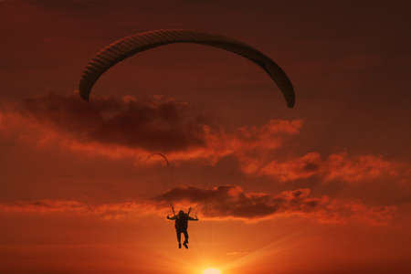 Paraglider flying against a sunsetの写真素材