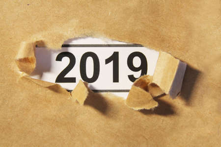 2019 appearing behind ripped brown paperの写真素材