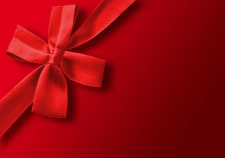 red gift ribbon wrapped around a red backgroundの写真素材