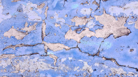 Old grunge wall of a background or texture painted in blue paint that cracked under the influence of timeの写真素材