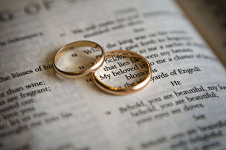 Two golden wedding rings on a Bible pageの写真素材