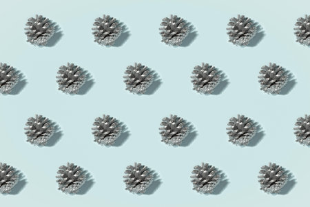 Minimalistic siver coated pine cones decorative pattern on a matte blue backdrop. Perfect design for...