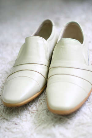 Pair of wedding mens white shoes is lying on a fur carpet and they are ready for a groom.の写真素材