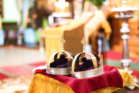 Two golden crown at wedding ceremony in beautiful interior of Saint Trinity Orthodox Convent in Riga, Latvia including candlesticks with many candles. Nice bokeh with copy space in the background.の写真素材