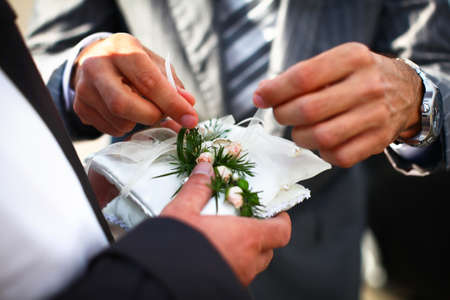 Groom and witness are finalizing preparation of golden rings before start of wedding ceremony.の写真素材