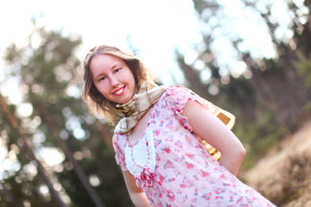 Sweet sexy woman in beautiful dress is standing in a sunshine against spring forest
