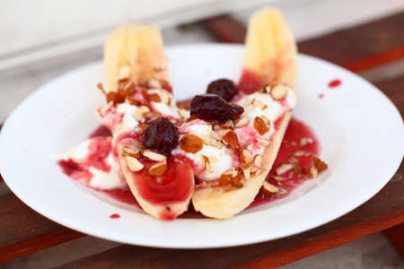 Cottage cheese fruit dessert with banana, cherry jam, almonds and creamの写真素材