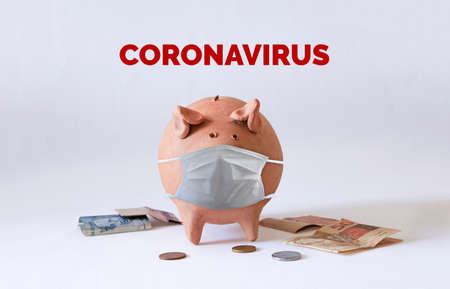 Pig coin with Coronavirus mask and Brazilian money and coins isolated.の写真素材