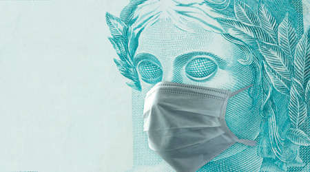 Coronavirus mask on Brazilian money scare. Concept of economy crisisの写真素材