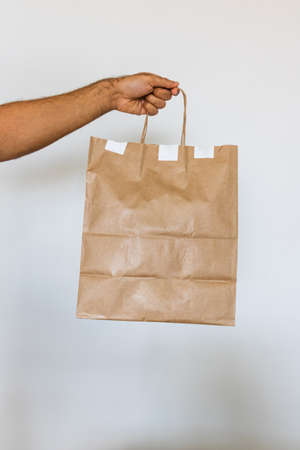 Holding a paper bag isolated. Delivery home food app concept image.の写真素材