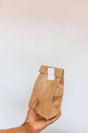 Holding a paper bag isolated. Delivery home food app concept image.の写真素材