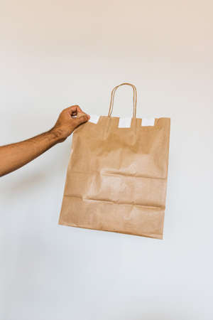 Holding a paper bag isolated. Delivery home food app concept image.の写真素材