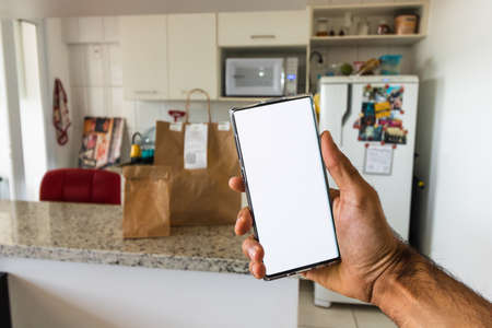 Ordering food online in a mobile, paper bah in background.の写真素材