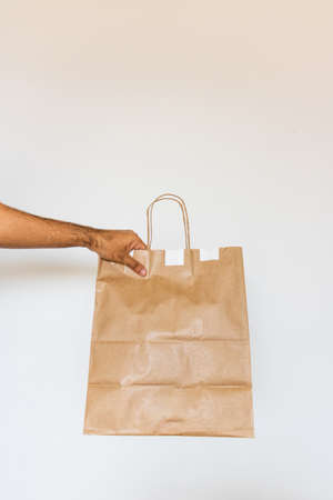 Holding a paper bag isolated. Delivery home food app concept image.の写真素材