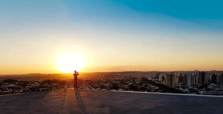 Silhouette of a man with glasses on top of a building.の写真素材