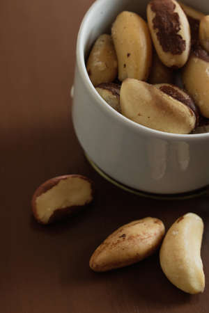 Brazilian nuts in a bowl on a wooden table.の写真素材