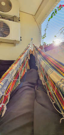 Legs resting in the hammock at morning sunrise.の写真素材