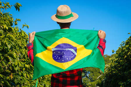 Holding a Brazil flag. Farmer at coffee plantation holding Brazilian flag.の写真素材