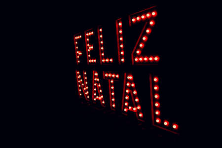 Merry christmas written in portuguese on neon red light. Christmas black background, space for text.の写真素材