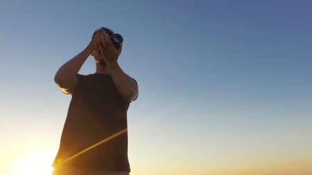 Silhouette of a photographer taking pictures on top of the building at sunsetの写真素材