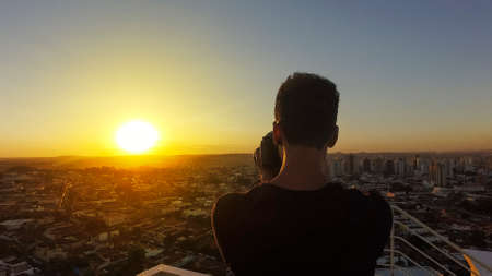 Silhouette of a photographer taking pictures on top of the building at sunsetの写真素材