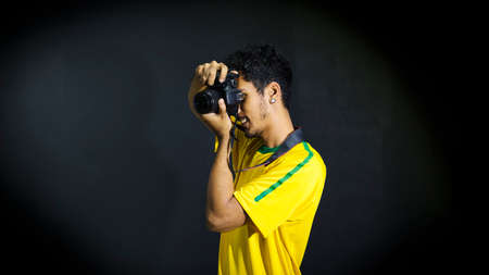 Tourist or fan in yellow uniform with camera and glasses celebrating on black backgroundの写真素材
