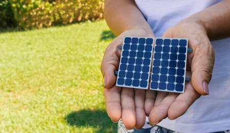 Holding solar energy photovoltaic panel at a green natural background - Concept Image of Sustainable Resourcesの写真素材