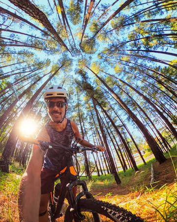 Black cyclist on forest trail taking a selfie on bike on sunny dayの写真素材