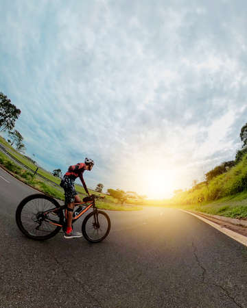 Black man with helmet and glasses riding a bicycle on the road.の写真素材