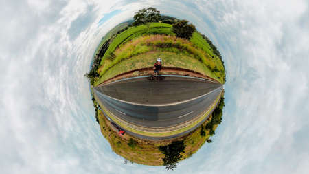 Black man with helmet and glasses riding a bicycle on the road.の写真素材
