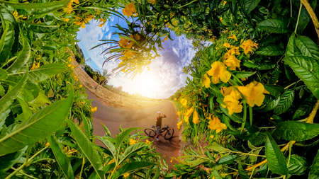 Black man with helmet and glasses riding a bicycle on the road. 360 flowers background concept.