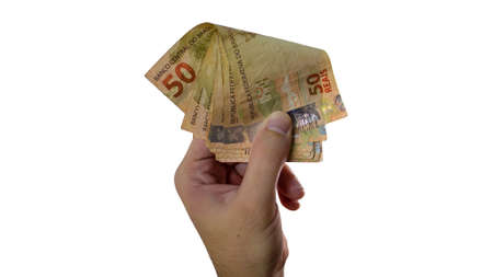 Holding Brazilian real money isolated on white background. Male hand holding cash note.