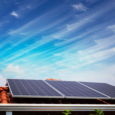 Solar panels on the red roof in a sunny and cloudy day.