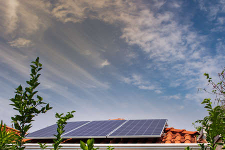 Solar panels on the red roof in a sunny and cloudy day.