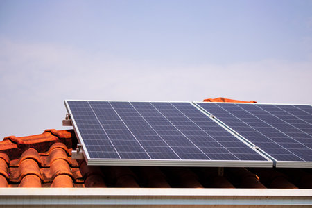 Solar panels on the red roof in a sunny and cloudy day.の写真素材