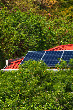 Solar panels on the red roof house in a sunny and cloudy day. Photovoltaic Solar Energy Instalation.の写真素材