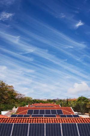 Solar panels Instalation on the roof of many houses in a sunny and cloudy day.