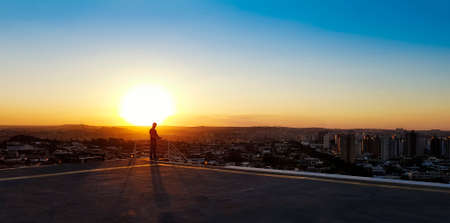 Silhouette of a man with glasses on top of a building.の写真素材