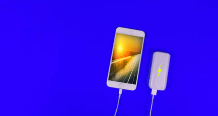 Solar Energy Battery Creative Concept Image. Solar powered cell phone plugged into a battery on blue...