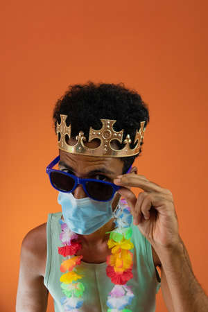 Black man in costume for carnival with pandemic mask isolated on orange background.の写真素材