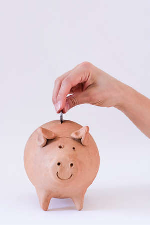 White Hand Putting Brazilian money in pig coin isolated on white backgroundの写真素材
