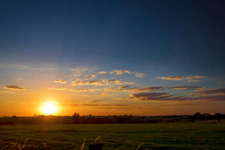 Dramatic Natural Sunset Sunrise Over farm field. Countryside Landscape Under Scenic Colorful Sky At Sundown.の写真素材