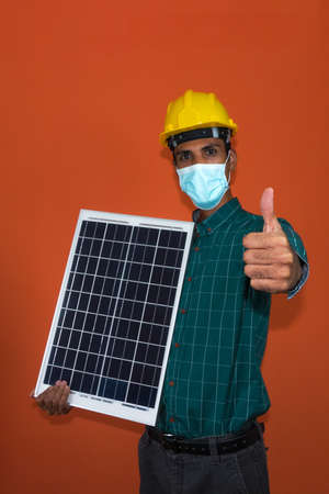 Worker With Helmet and Pandemic Mask Holding a Solar Photovoltaic Panel isolated. Solar Worker...