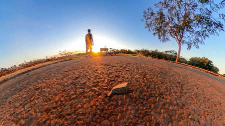 Man with bicycle on little planet with trees, soft blue sky and sunset. Bike concept image.の写真素材
