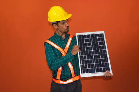 Solar worker in protective work clothes holding photovoltaic panel isolated. Concept of designing power plants.の写真素材